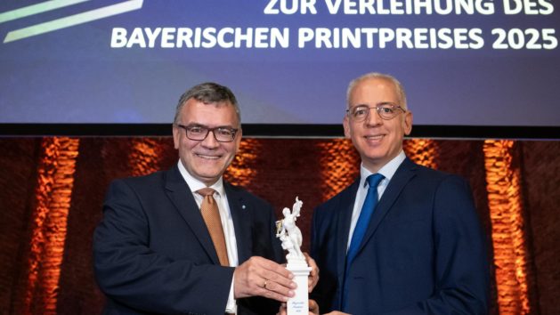 Bayerischer Printpreis 2025: Medienminister Dr. Florian Herrmann übergibt den Ehrenpreis des Bayerischen Ministerpräsidenten an Roland Schreiner, Geschäftsführender Gesellschafter der Schreiner Group in Oberschleißheim bei München.