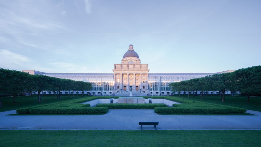 Blick vom Hofgarten auf die Bayerische Staatskanzlei. Historisches Herzstück bildet der Kuppelbau des alten Armeemuseums, an den sich die beiden gläsernen Flügelbauten anschließen.