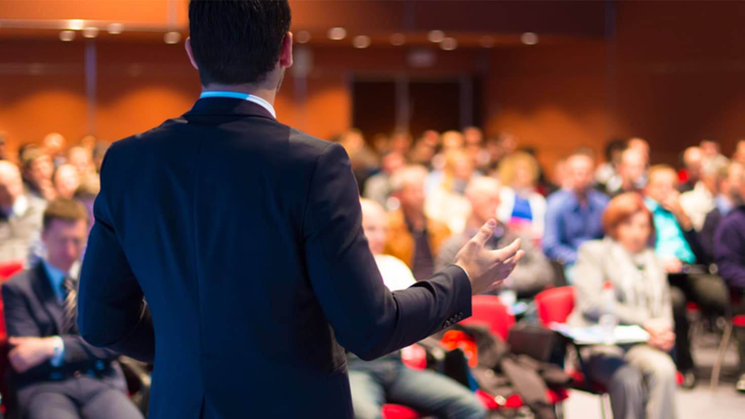 Ein Mann steht vor vielen Personen bei einer Fortbildungsveranstaltung. © Matej Kastelic - Fotolia