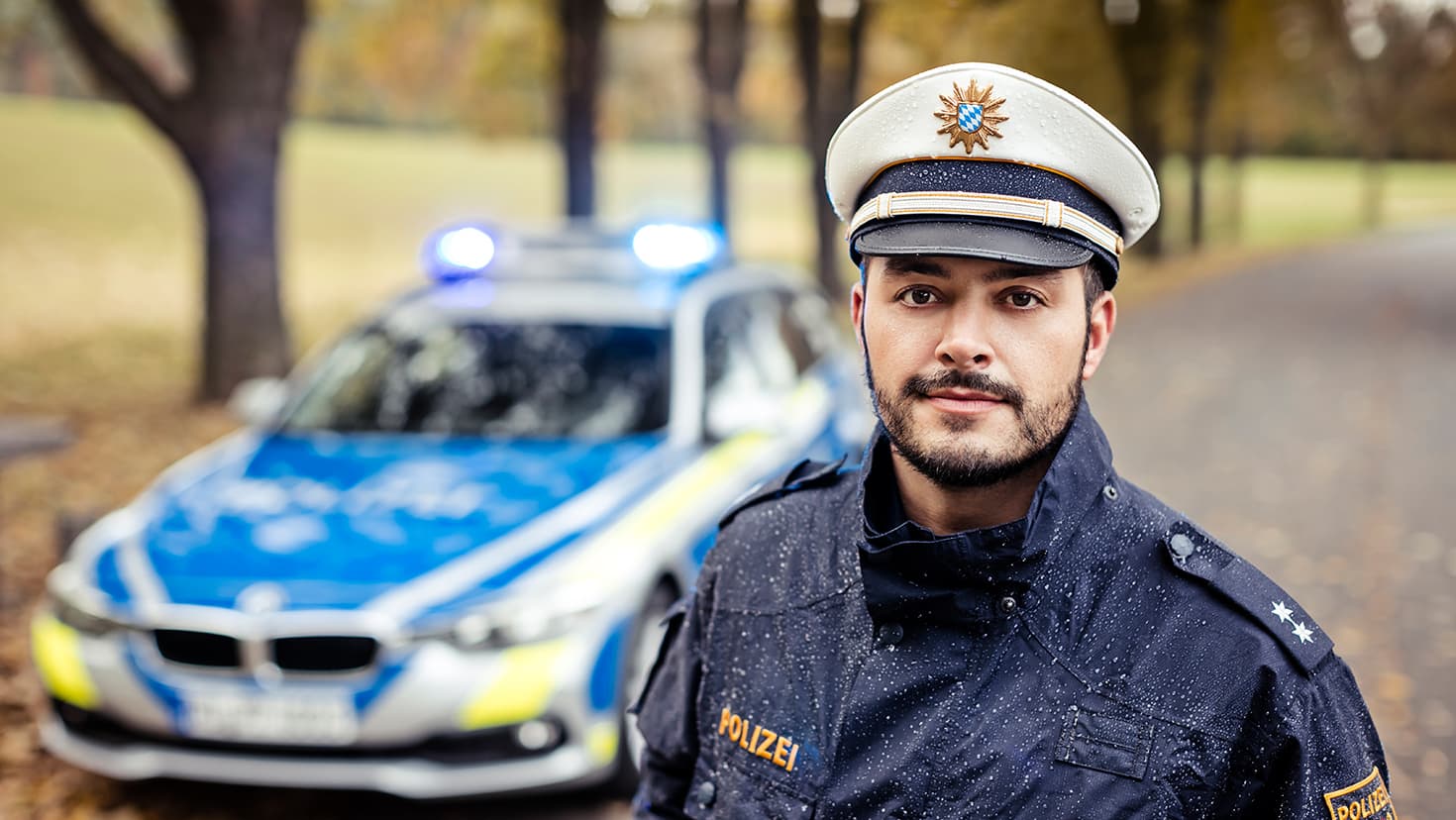 Bayerischer Polizist vor einem Streifenwagen. © Polizei Bayern