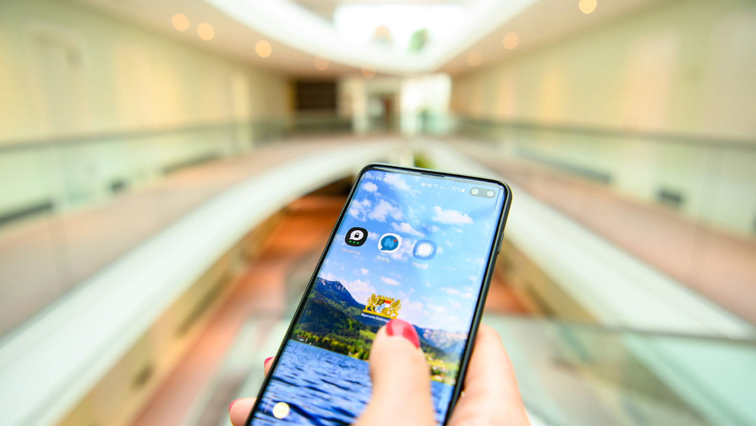 In der Staatskanzlei: Eine Frau hält ein Smartphone. Auf dem Smartphone sind die Apps der Messenger-Dienste Threema, Notify und Signal sowie vor einem Landschaftsbild.