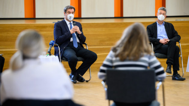 Ministerpräsident Dr. Markus Söder, MdL (2. von links), und Kultusminister Professor Dr. Michael Piazolo, MdL (rechts), besuchen eine Willkommensgruppe am Gymnasium Trudering in München.