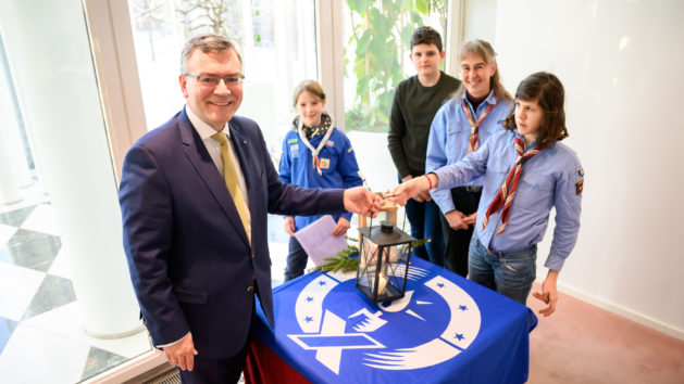 Staatsminister Dr. Florian Herrmann, MdL (links), nimmt das Friedenslicht aus Bethlehem entgegen.