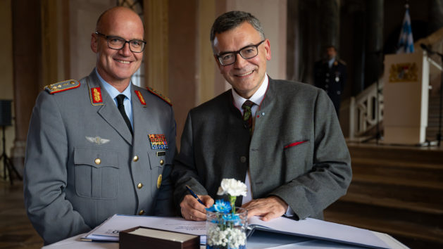Im Beisein vom Kommandeur der Sanitätsakademie der Bundeswehr, Generalstabsarzt Dr. Hans-Ulrich Holtherm (links), trägt sich Staatsminister Dr. Florian Herrmann (rechts) in das Gästebuch ein.