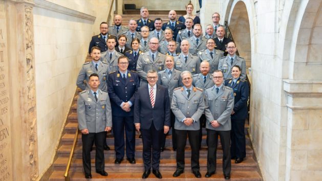 Gruppenbild zur Verleihung der Offizierbriefe: Staatsminister Dr. Florian Herrmann und der stellvertretende Kommandeur der Sanitätsakademie, Generalarzt Dirk-Friedrich Dr. Klagges mit den Offizieranwärterinnen und -anwärtern.