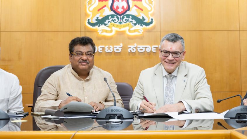 Der Industrieminister des Bundesstaates Karnataka, M.B. Patil, links, und Staatsminister Florian Herrmann, rechts, unterzeichnen eine gemeinsame Absichtserklärung zur Bekräftigung und Weiterentwicklung der Partnerschaft Bayern-Karnataka.