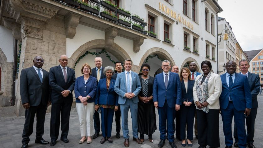 Gruppenbild vor dem Münchner Hofbräuhaus: Europaminister Eric Beißwenger und Staatskanzleiminister Dr. Florian Herrmann mit der Delegation von Botschafterrinnen und Botschaftern bei den Vereinten Nationen.