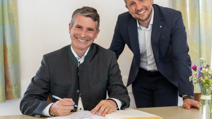 Im Beisein vom 1. Bürgermeister des Marktes Altusried, Max Boneberger (rechts), trägt sich Europaminister Eric Beißwenger (links) in das Gästebuch des Marktes Altusried ein.