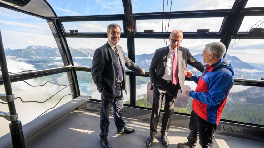 Während der Gondelfahrt zur Zugspitze: Ministerpräsident Dr. Markus Söder und Bundeskanzler Friedrich Merz im Gespräch mit dem Vorsitzenden der Bergwacht Bayern, Thomas Lobensteiner.
