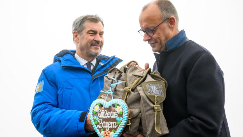 Ministerpräsident Dr. Markus Söder überreicht Bundeskanzler Friedrich Merz ein Gastgeschenk.