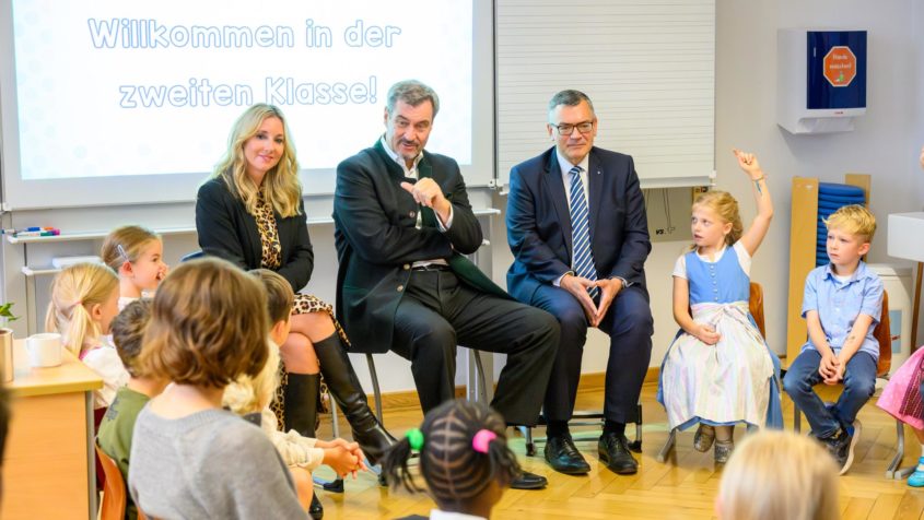 Bei ihrem Besuch in der Grundschule and er Kirchenstraße in München kommen Kultusministerin Anna Stolz, Ministerpräsident Dr. Markus Söder und Staatskanzleiminister Dr. Florian Herrmann mit den Schülerinnen und Schülern ins Gespräch.