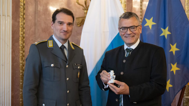Der Landesvorsitzende des Verbands der Reservisten der Deutschen Bundeswehr e.V. in Bayern, Major d.R. Fabian Forster (links), überreicht Staatsminister Dr. Florian Herrmann (rechts) den Bayerischen Porzellanlöwen im Prinz-Carl-Palais.