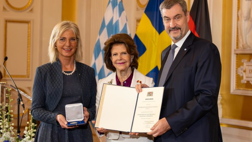 Sozialministerin Ulrike Scharf (links) und Ministerpr&auml;sident Dr. Markus S&ouml;der (rechts) zeichnen Ihre Majest&auml;t K&ouml;nigin Silvia von Schweden (Mitte) mit der Bayerischen Staatsmedaille f&uuml;r soziale Verdienste aus.