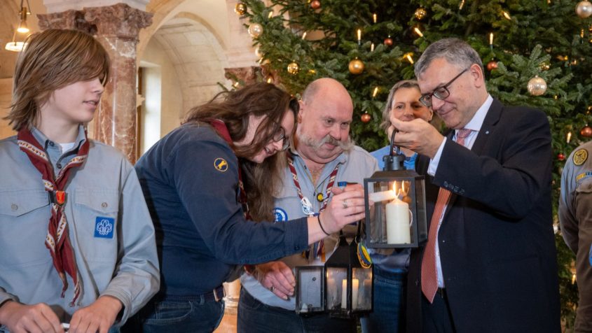 Staatsminister Dr. Florian Herrmann empf&auml;ngt das &bdquo;Friedenslicht aus Bethlehem&ldquo; durch die Pfadfinder.