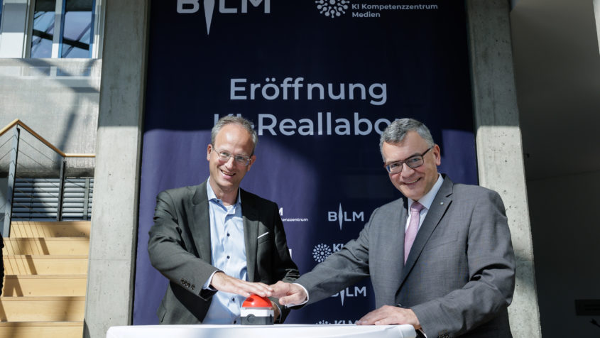 BLM-Präsident Dr. Thorsten Schmiege (links) und Medienminister Dr. Florian Herrmann (rechts) eröffnen das KI-Reallabor vom KI-Kompetenzzentrum Medien (KI.M). © Stefan Heigl/BLM